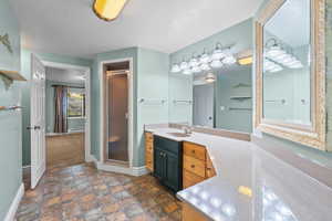 Full bath featuring vanity, a stall shower, dark stone finish flooring, and a baseboard radiator