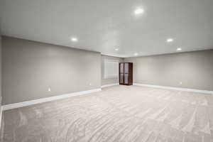Below grade area featuring recessed lighting and light carpet