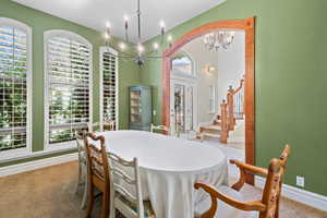 Carpeted dining space featuring stairway and a chandelier