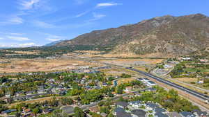 Aerial view of property and surrounding area featuring nearby suburban area and a mountain backdrop