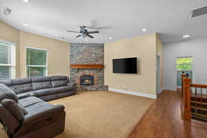 Living room with wood finished floors, a fireplace, ceiling fan, recessed lighting, and carpet floors