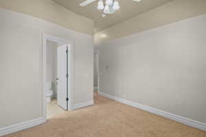 Unfurnished bedroom featuring light carpet, a ceiling fan, and ensuite bathroom