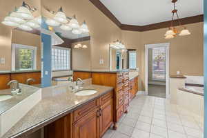 Bathroom with a chandelier, light tile patterned floors, vanity, and a garden tub