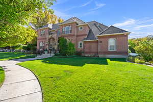 View of front of home featuring brick siding, a front lawn, and roof with shingles