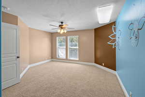 Unfurnished room featuring carpet flooring, a textured ceiling, and ceiling fan