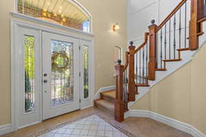 Foyer featuring inlaid floor details, light tile patterned flooring, and stairway