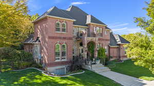 View of front facade featuring a front yard, brick siding, and a balcony
