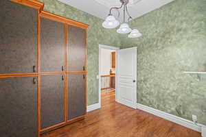 Unfurnished bedroom featuring dark wood-type flooring and a chandelier