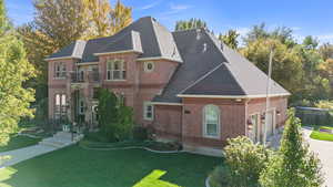 View of front of home featuring a front lawn, brick siding, concrete driveway, roof with shingles, and an attached garage