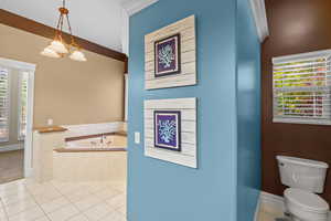 Bathroom featuring tile patterned floors, a bath, and a chandelier