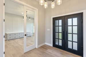 Doorway featuring french doors, wood finished floors, and a chandelier