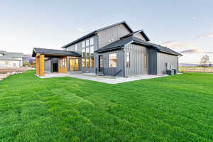 Back of house with a patio, a yard, board and batten siding, and a shingled roof