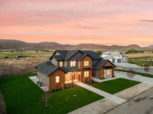Modern inspired farmhouse featuring concrete driveway, roof with shingles, a mountain view, and a lawn