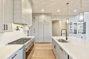 Kitchen featuring premium appliances, light stone countertops, recessed lighting, light wood-style flooring, and decorative light fixtures