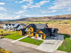 View of front of home featuring roof with shingles, board and batten siding, a mountain view, and concrete driveway