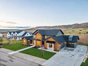 Modern farmhouse style home featuring roof with shingles, a lawn, driveway, a standing seam roof, and a mountain view