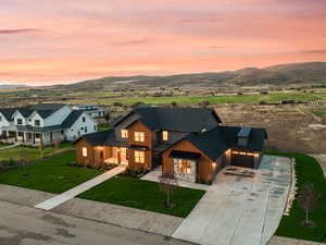 View of front of home featuring a shingled roof, concrete driveway, a front yard, and a mountain view