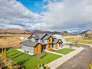 Modern farmhouse with a mountain view, a front yard, and a shingled roof