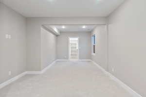 Empty room with light colored carpet and recessed lighting
