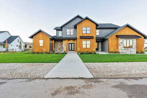 Modern farmhouse featuring a standing seam roof, a metal roof, board and batten siding, and stone siding