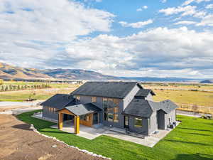 Back of property featuring a shingled roof, a view of countryside, a patio area, and a mountain view