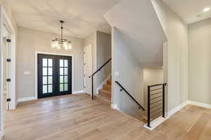 Entrance foyer featuring light wood-type flooring, french doors, and a chandelier
