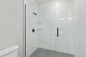 Full bath featuring a stall shower and toilet