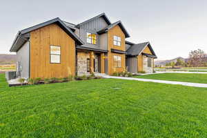 Modern farmhouse featuring a front yard, a mountain view, and board and batten siding