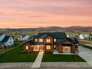 Modern inspired farmhouse featuring concrete driveway, a mountain view, stone siding, board and batten siding, and a shingled roof