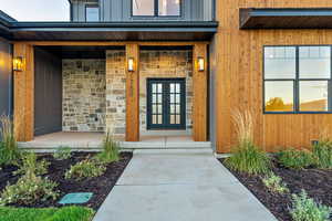 View of exterior entry featuring covered porch and stone siding