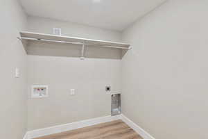 Laundry area with electric dryer hookup, light wood finished floors, and washer hookup