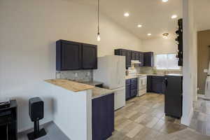 Kitchen with tasteful backsplash, a peninsula, hanging light fixtures, white appliances, and a kitchen breakfast bar
