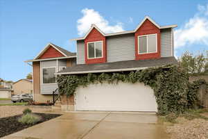 View of front of property featuring concrete driveway, a garage, and a shingled roof