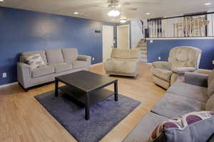 Living area with recessed lighting, light wood-type flooring, ceiling fan, and stairway