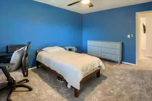 Carpeted bedroom with an office area and a ceiling fan