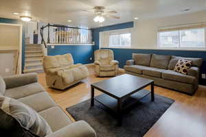 Living area with light wood-style floors, stairs, ceiling fan, and recessed lighting
