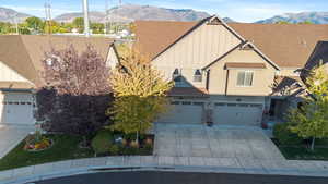View of front facade with a mountain view, board and batten siding, driveway, a garage, and stucco siding