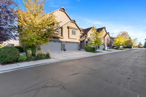 View of front facade with a residential view, a garage, concrete driveway, stone siding, and stucco siding