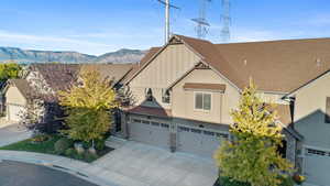 View of front of property with board and batten siding, an attached garage, concrete driveway, stone siding, and a mountain view