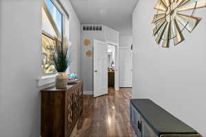 Hallway featuring plenty of natural light and dark wood-style flooring
