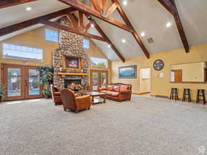 Living room featuring french doors, a stone fireplace, high vaulted ceiling, carpet flooring, and recessed lighting