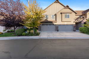 View of front of home featuring an attached garage, board and batten siding, driveway, stone siding, and stucco siding