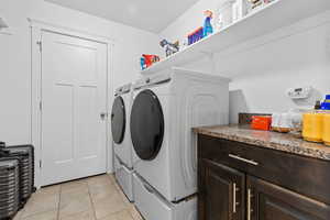 Laundry area featuring light tile patterned floors and independent washer and dryer