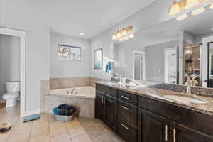 Full bathroom featuring light tile patterned floors, a bath, a shower stall, and double vanity