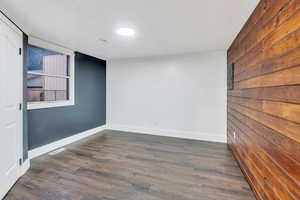 Unfurnished room with dark wood finished floors and wooden walls