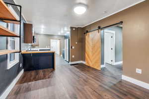 Kitchen featuring a barn door, a peninsula, dark wood-style flooring, and freestanding refrigerator