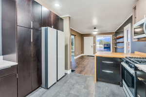 Kitchen with range with gas cooktop, freestanding refrigerator, stainless steel microwave, and modern cabinets