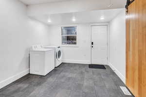 Laundry area featuring a barn door, independent washer and dryer, and recessed lighting