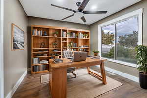 Home office with dark wood-style flooring and a ceiling fan