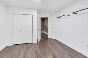 Unfurnished bedroom featuring dark wood-style flooring and a closet